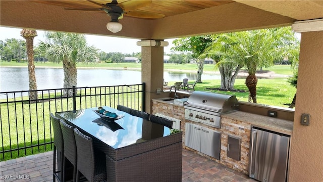 view of patio with area for grilling, grilling area, a water view, fence, and outdoor dining area