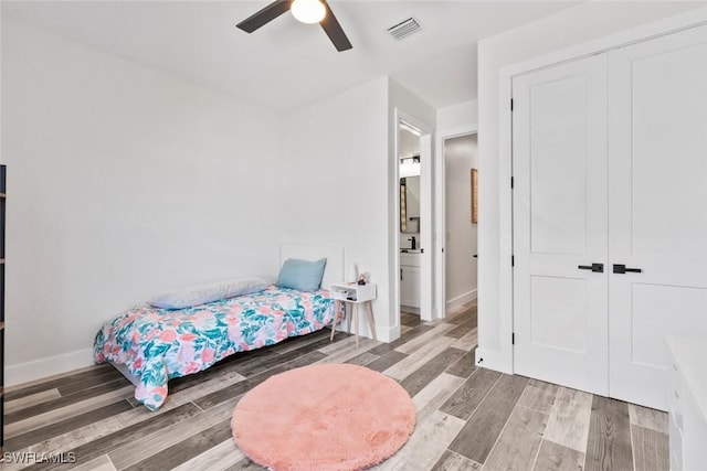 bedroom featuring baseboards, visible vents, wood finish floors, ceiling fan, and a closet