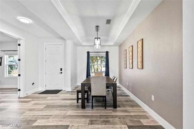 dining area featuring a raised ceiling, wood finished floors, visible vents, and a wealth of natural light