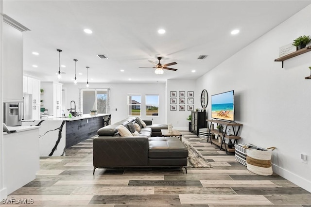 living room featuring recessed lighting, visible vents, and light wood-type flooring