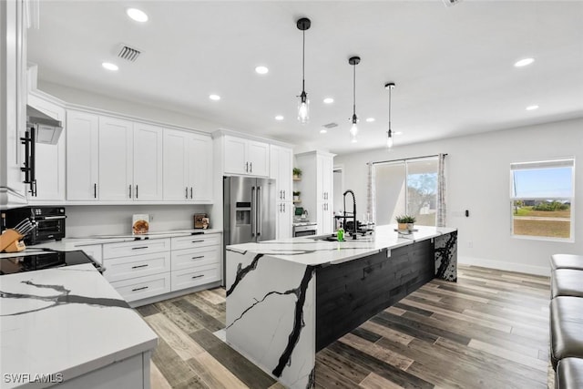 kitchen featuring visible vents, a sink, light wood-style floors, high quality fridge, and white cabinets