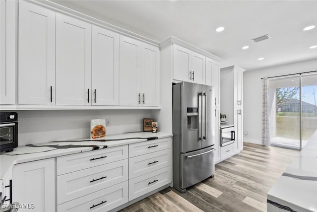 kitchen featuring light wood-type flooring, visible vents, recessed lighting, stainless steel fridge, and white cabinets