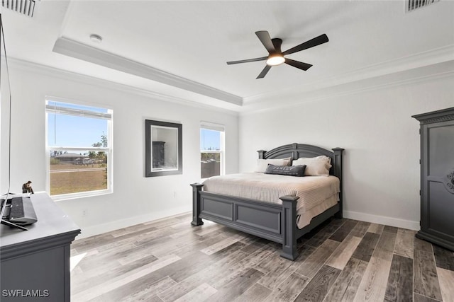 bedroom featuring a tray ceiling, multiple windows, and visible vents