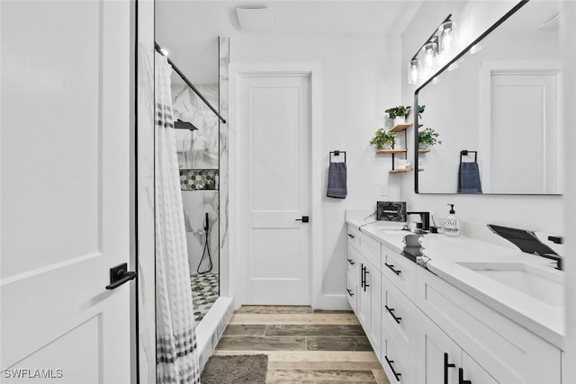 bathroom featuring a sink, double vanity, wood finished floors, and a shower stall