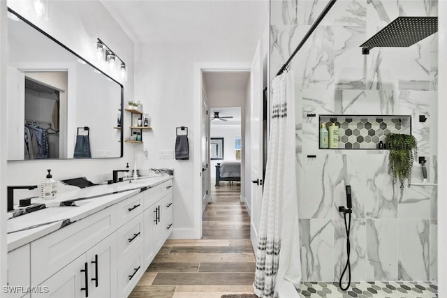 ensuite bathroom featuring a marble finish shower, double vanity, wood finished floors, ensuite bath, and a ceiling fan