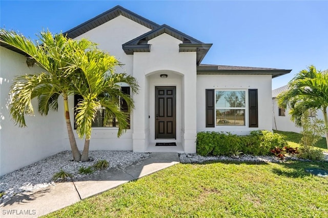 view of exterior entry featuring stucco siding and a yard