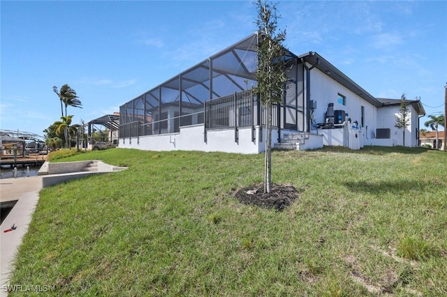 back of house with glass enclosure and a lawn