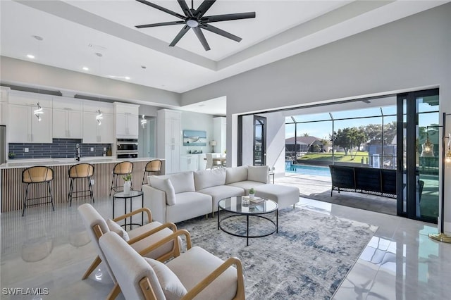 living area with recessed lighting, marble finish floor, a towering ceiling, and ceiling fan