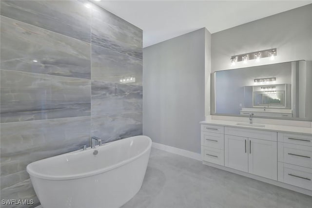 full bathroom featuring baseboards, a soaking tub, tile walls, and vanity