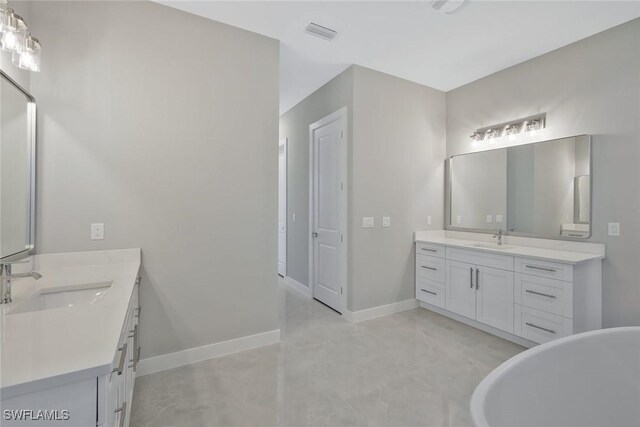 full bathroom featuring two vanities, baseboards, and a sink