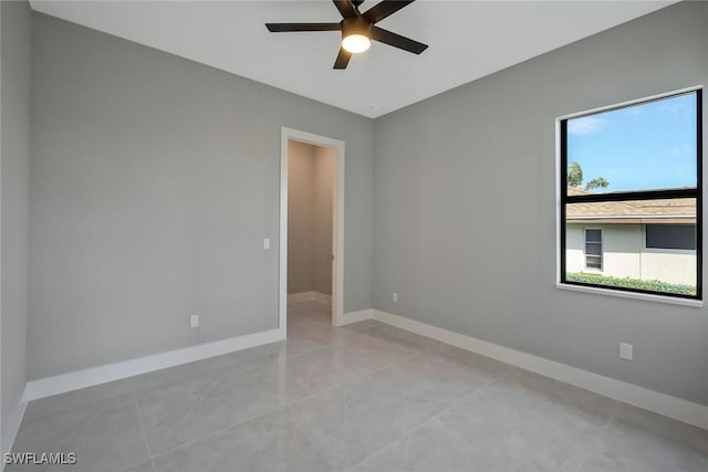 spare room featuring light tile patterned flooring, ceiling fan, and baseboards