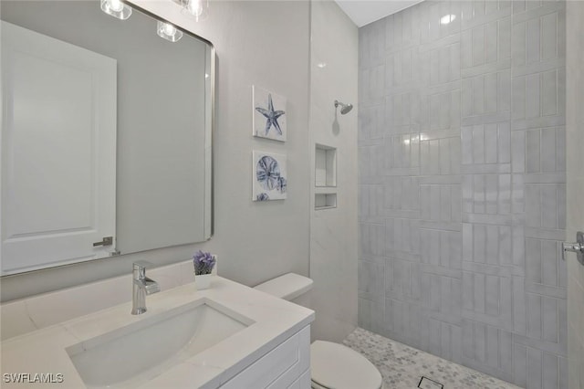 full bathroom featuring vanity, toilet, and tiled shower