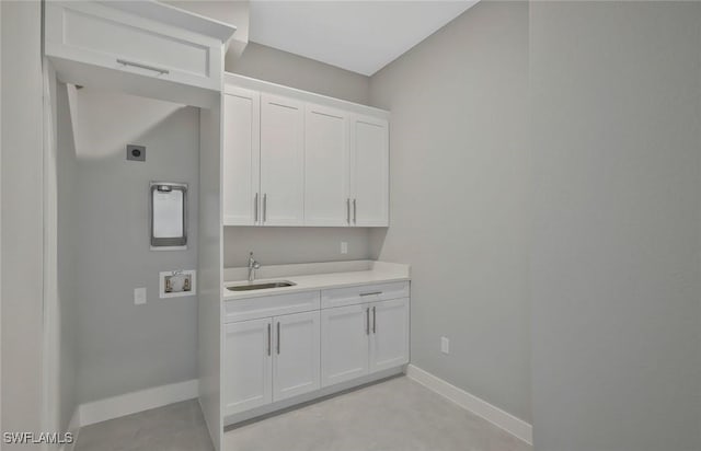 washroom with baseboards, cabinet space, electric dryer hookup, washer hookup, and a sink