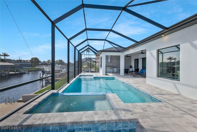 view of swimming pool featuring a water view, a pool with connected hot tub, ceiling fan, a patio, and a lanai