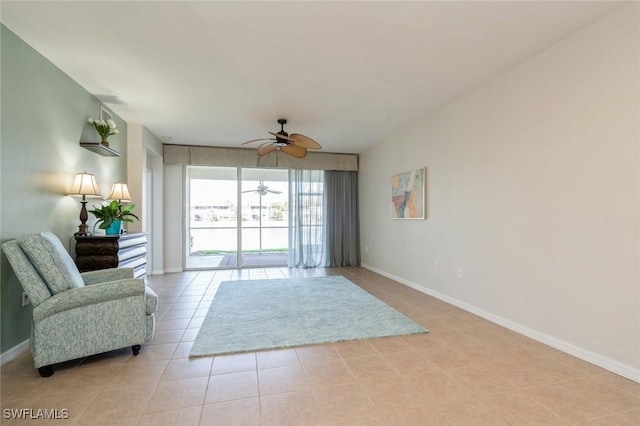 sitting room featuring a ceiling fan, light tile patterned flooring, and baseboards