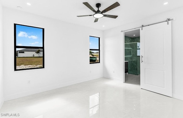 empty room featuring ceiling fan, a barn door, recessed lighting, and baseboards