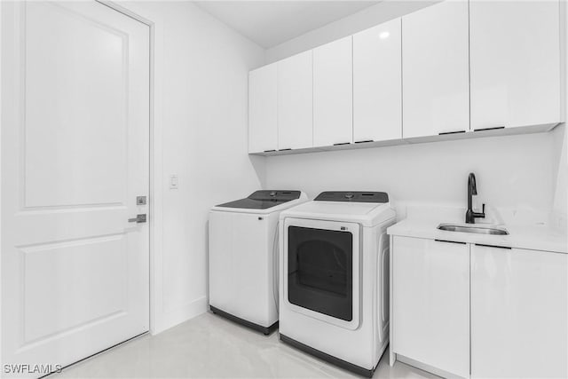 clothes washing area with cabinet space, baseboards, washer and clothes dryer, and a sink