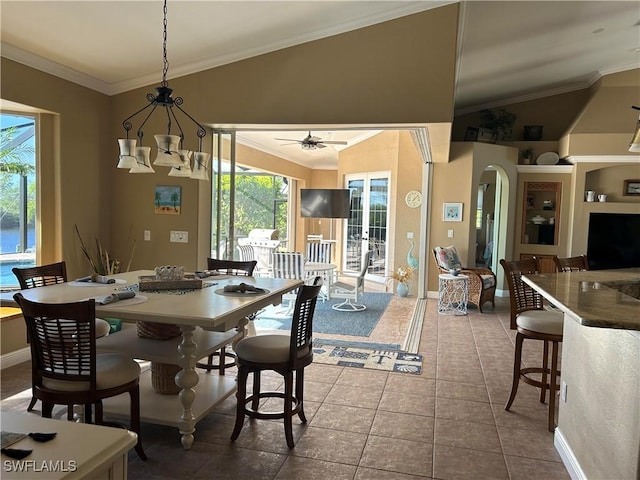 dining area with arched walkways, crown molding, and lofted ceiling