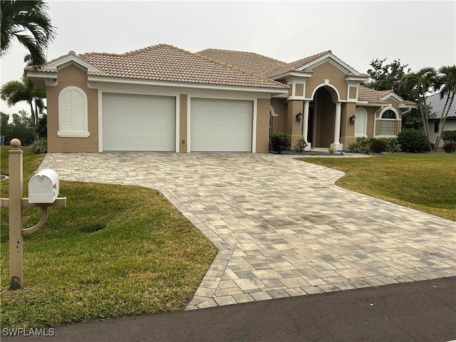 mediterranean / spanish-style house with a garage, stucco siding, decorative driveway, and a front yard