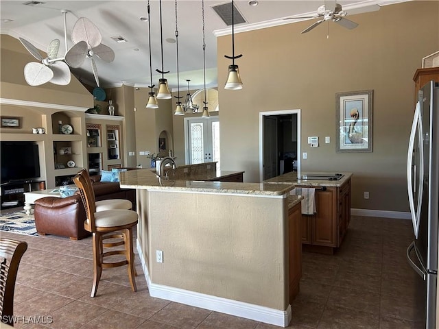 kitchen featuring visible vents, a ceiling fan, freestanding refrigerator, a large island with sink, and dark tile patterned floors