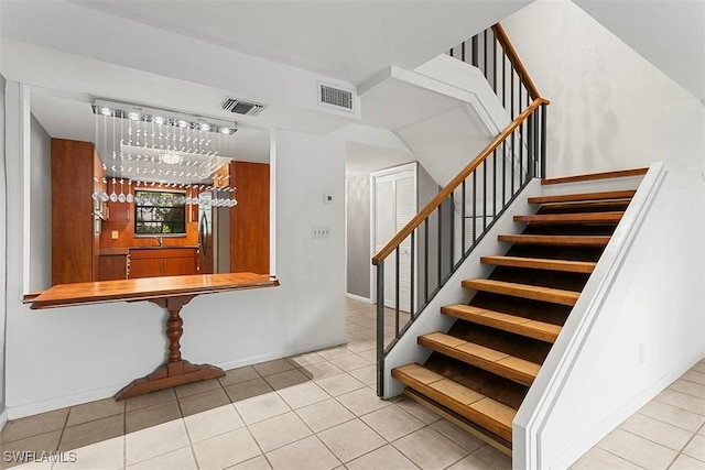 stairs featuring bar area, tile patterned flooring, visible vents, and baseboards