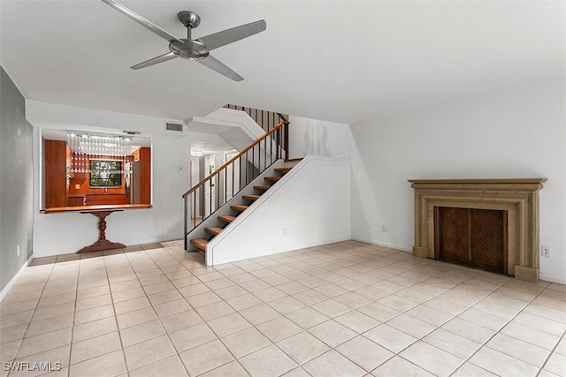 unfurnished living room with tile patterned flooring, visible vents, ceiling fan, and stairs