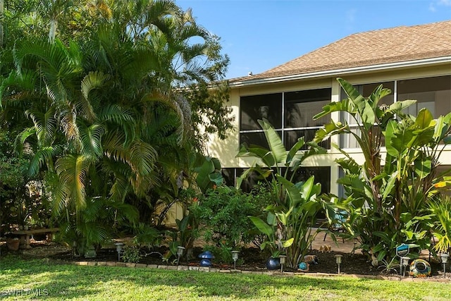 view of property exterior with a shingled roof and a sunroom