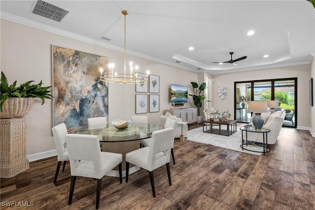 dining space with visible vents, a raised ceiling, wood finished floors, and ornamental molding