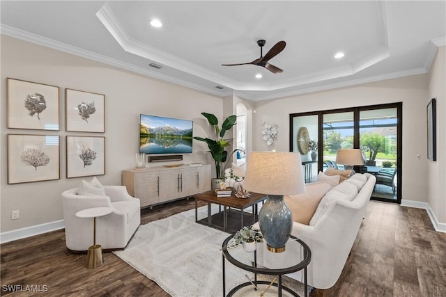 living room featuring a tray ceiling, crown molding, and wood finished floors