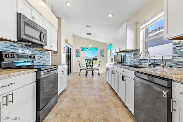 kitchen with lofted ceiling, decorative backsplash, white cabinets, stainless steel appliances, and a sink