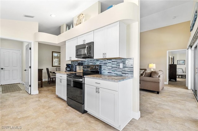 kitchen with visible vents, black range with electric stovetop, white cabinetry, stainless steel microwave, and backsplash