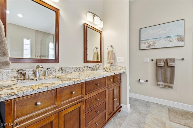 bathroom featuring double vanity, baseboards, and a sink