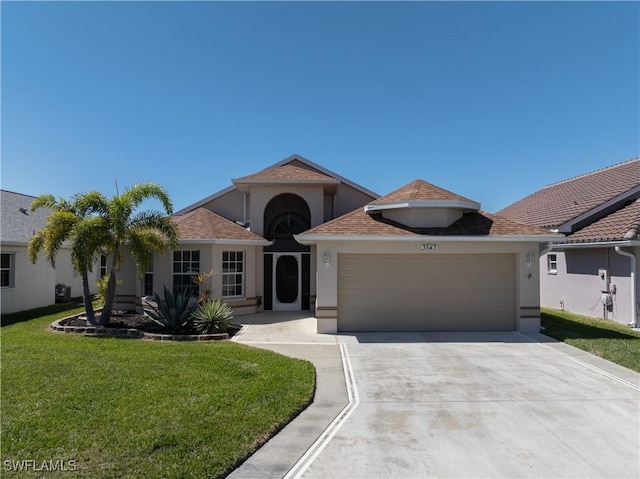 mediterranean / spanish house featuring a front lawn, a garage, driveway, and stucco siding