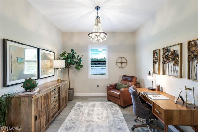 office space with a chandelier, light wood finished floors, and baseboards