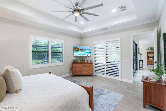 bedroom featuring light wood-style flooring, visible vents, a raised ceiling, and crown molding