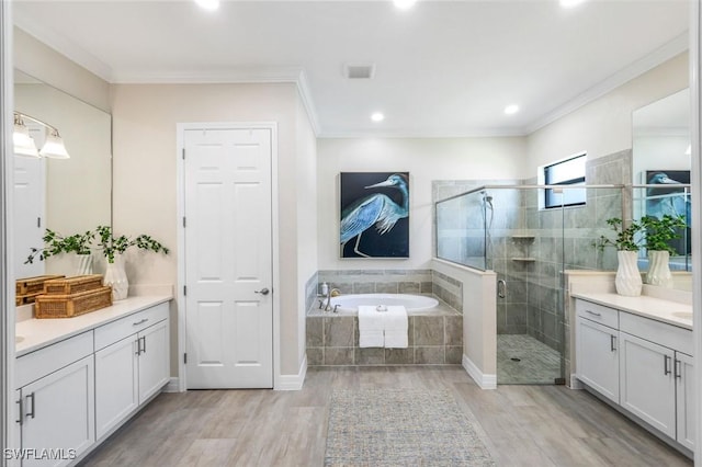 bathroom featuring a garden tub, crown molding, a shower stall, vanity, and wood finished floors