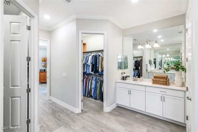 bathroom featuring baseboards, visible vents, ornamental molding, a spacious closet, and vanity