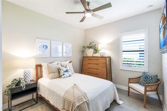 bedroom with a ceiling fan, baseboards, and wood finished floors