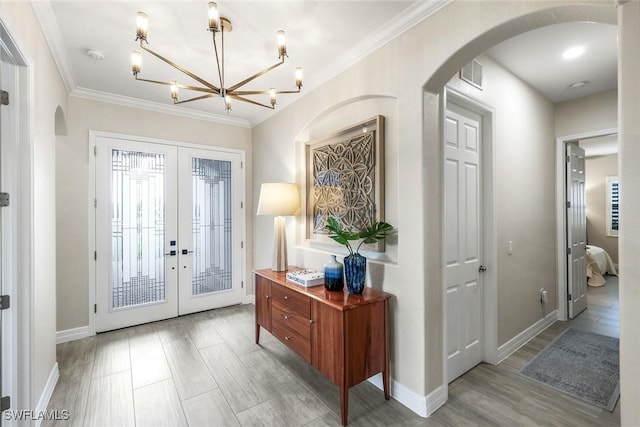 foyer entrance with arched walkways, french doors, wood finished floors, and crown molding