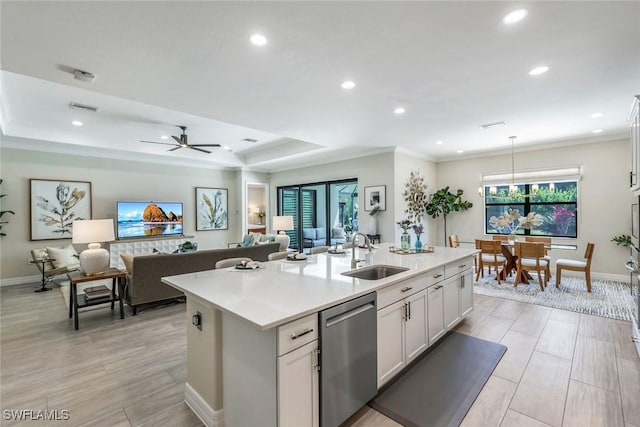 kitchen featuring an island with sink, light countertops, crown molding, stainless steel dishwasher, and a sink