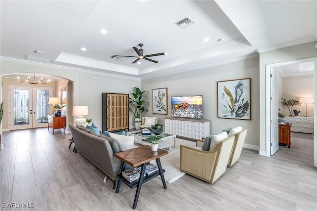 living room featuring arched walkways, visible vents, french doors, a tray ceiling, and crown molding