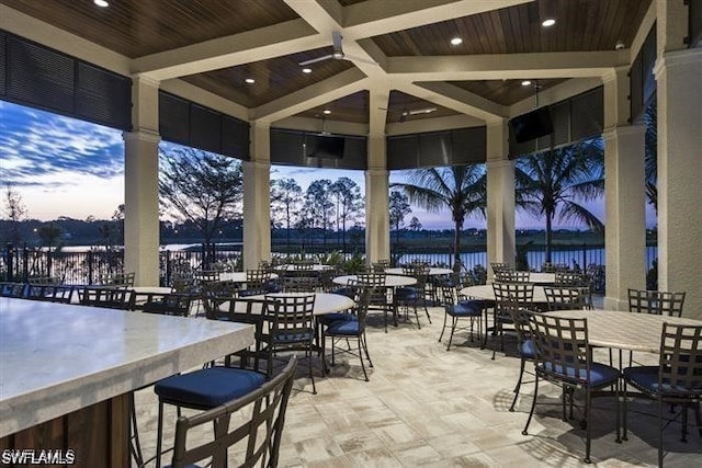 patio terrace at dusk featuring a water view and outdoor dry bar