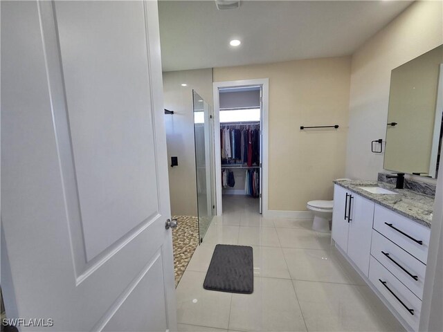 bathroom with a spacious closet, toilet, a stall shower, vanity, and tile patterned flooring