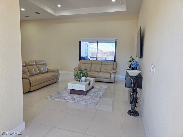 living room with visible vents, baseboards, a raised ceiling, tile patterned floors, and recessed lighting