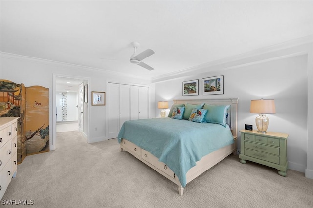 bedroom featuring ornamental molding, a ceiling fan, a closet, baseboards, and light colored carpet