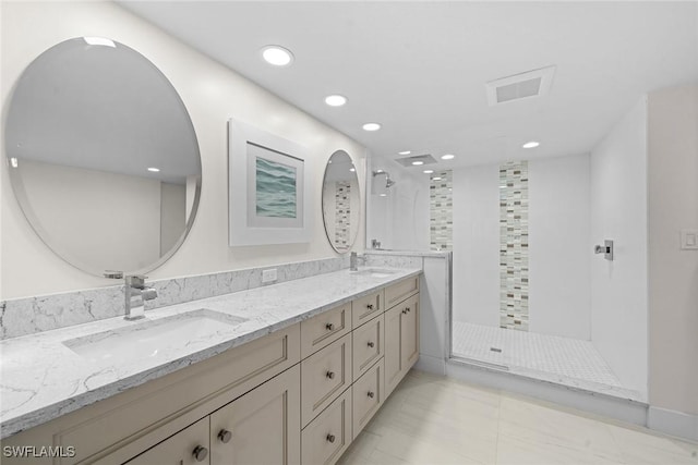 bathroom featuring a sink, double vanity, and a tile shower