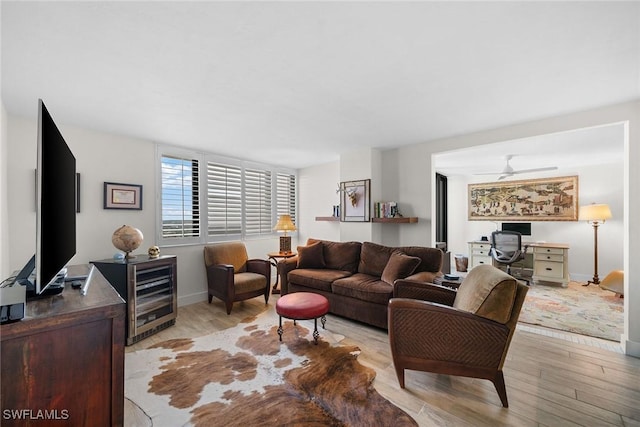 living area featuring baseboards, light wood-style floors, and a ceiling fan