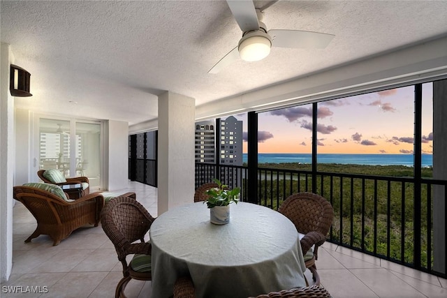 dining room with a textured ceiling, light tile patterned floors, a water view, and ceiling fan