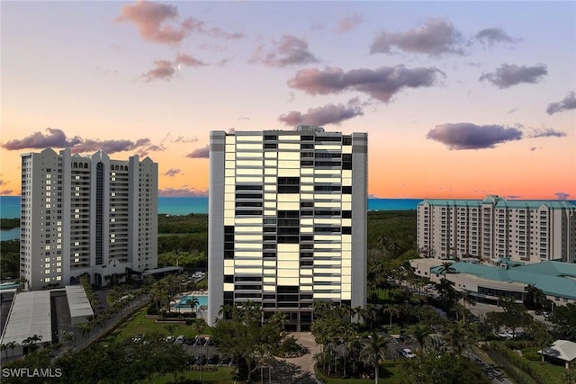 property at dusk with a city view and a water view