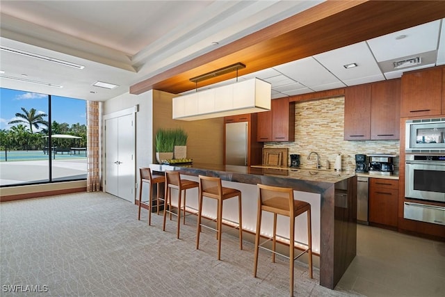 kitchen featuring tasteful backsplash, appliances with stainless steel finishes, a breakfast bar area, and a warming drawer